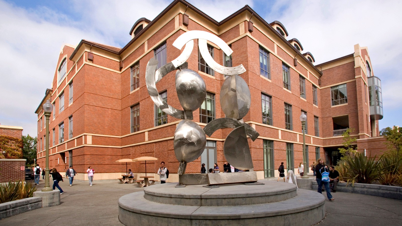 Modern stainless-steel sculpture displayed prominently in front of an SRJC academic building.