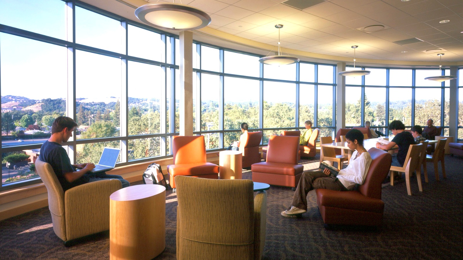 Students studying inside Doyle Library with large windows overlooking the hills.