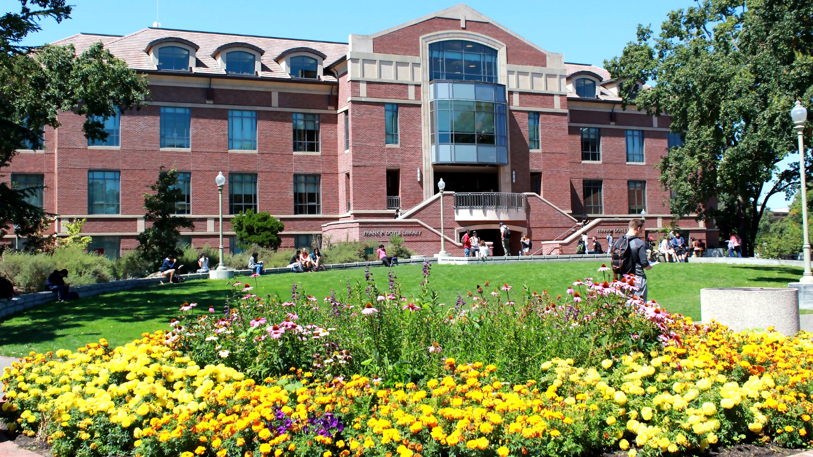 A wide view of SRJC's main quad with students relaxing on the lawn in front of the Doyle Library.