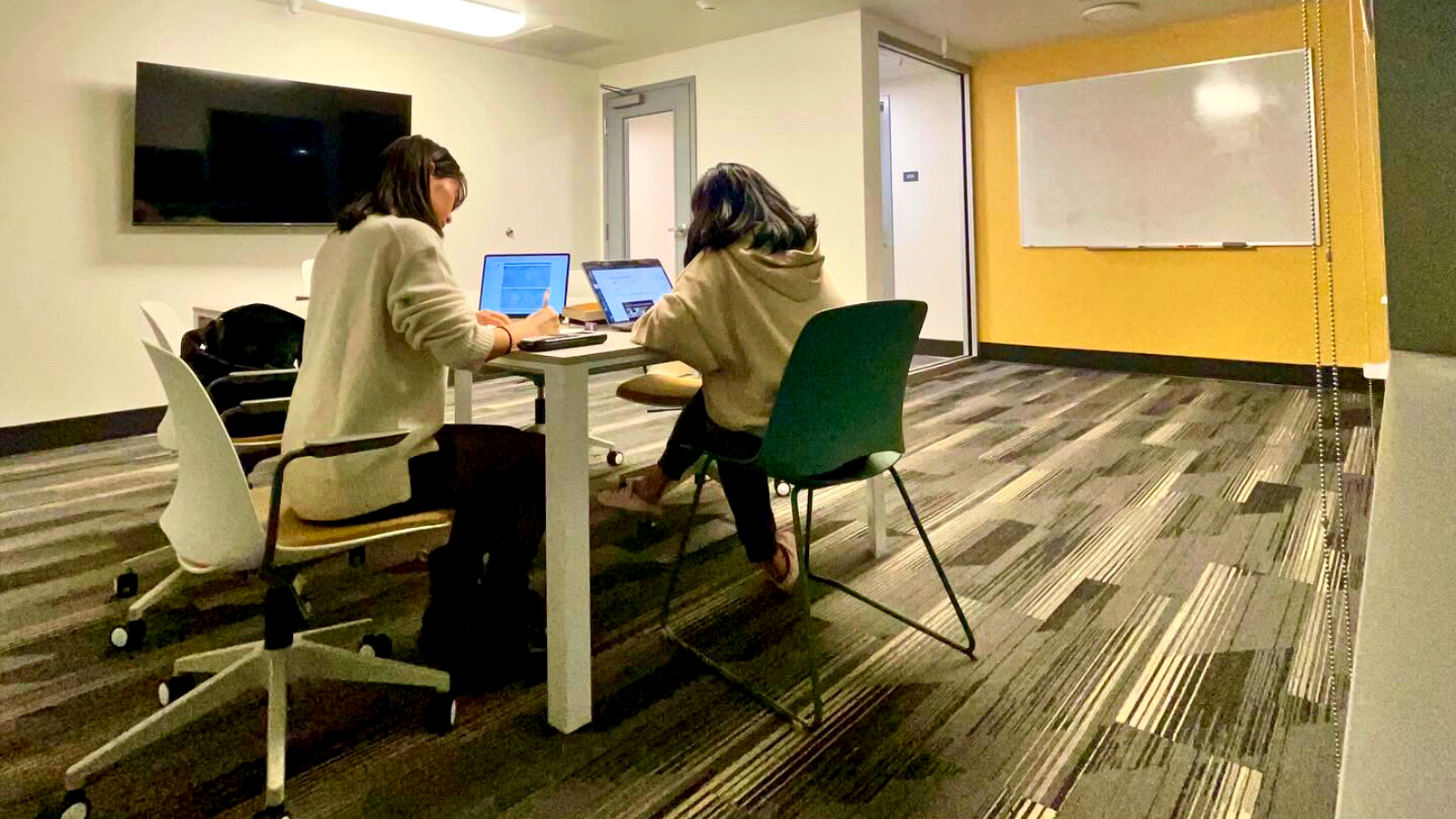Two students studying at a table in the residence hall lounge area.